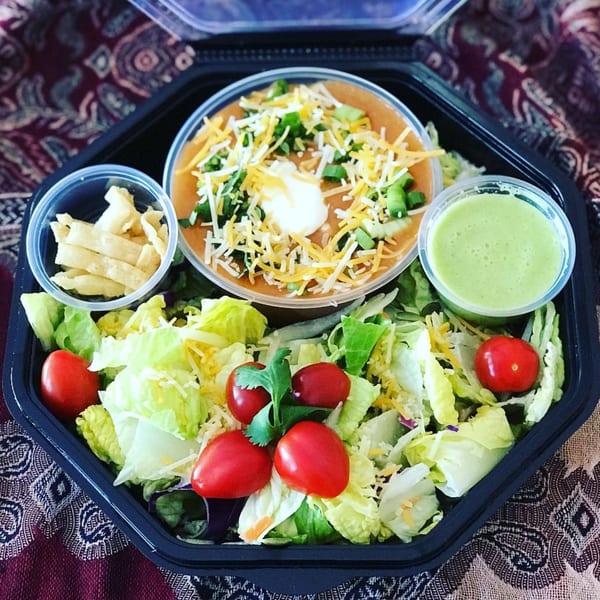 Eats Meets West Bowls' healthy meal with soup, salad, dressing, and tortilla strips in a black container.