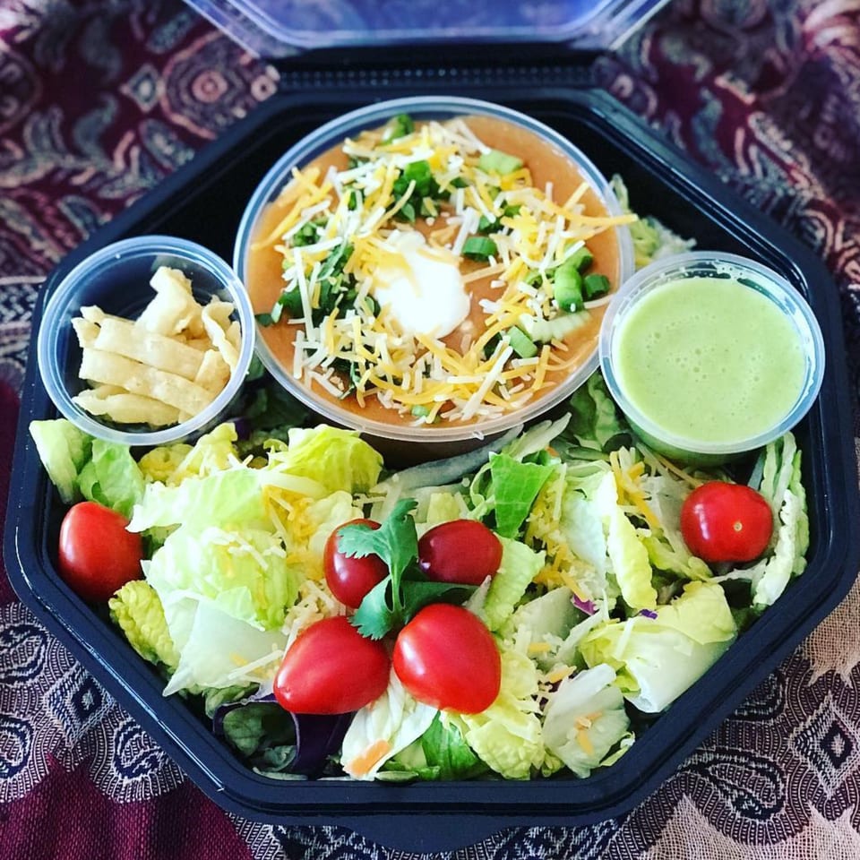 Eats Meets West Bowls' healthy meal with soup, salad, dressing, and tortilla strips in a black container.