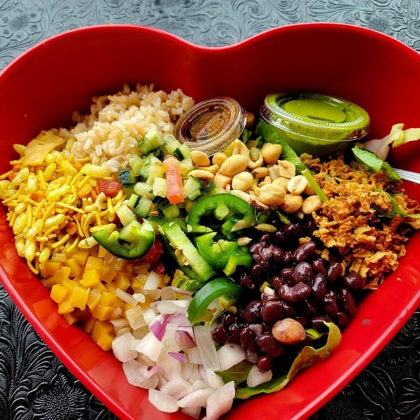 A vibrant, healthy bowl from Eats Meets West Bowls, filled with diverse ingredients in a heart-shaped dish.