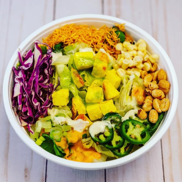A vibrant Eats Meets West Bowl with purple cabbage, mango, corn, peanuts, and jalapeños.