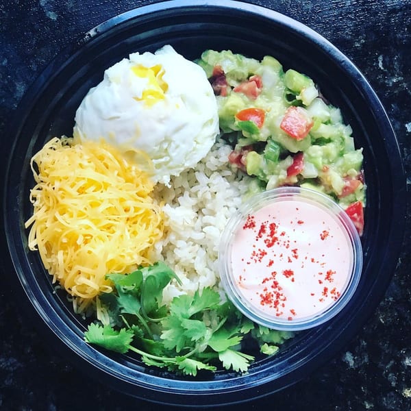 Eats Meets West Bowls' healthy bowl with rice, guacamole, poached egg, shredded cheese, cilantro, and sauce.
